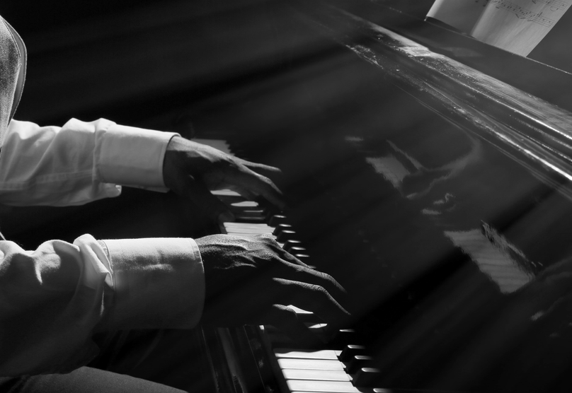 Hands playing piano in darkness